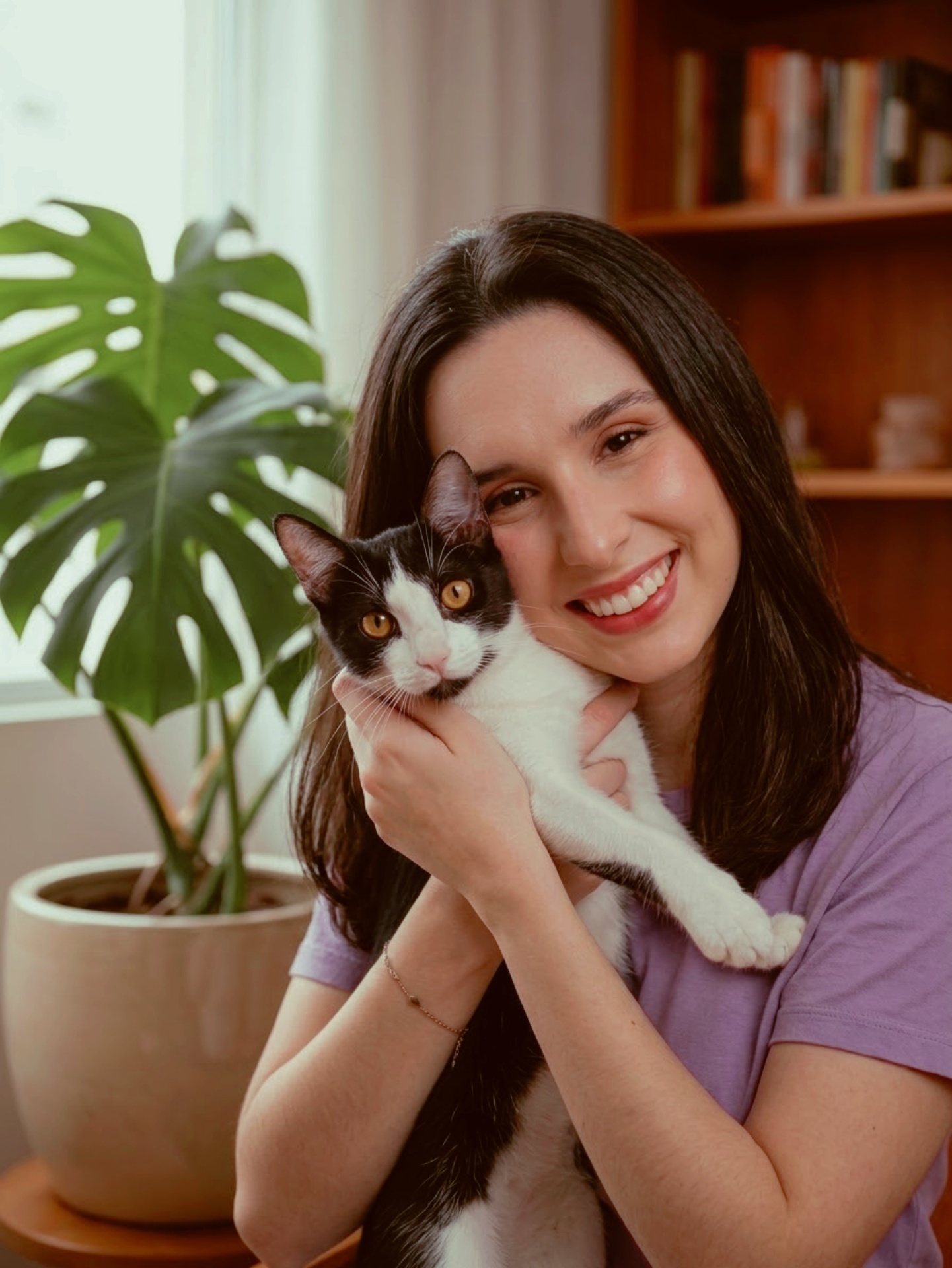 catarina, médica veterinária e pet sitter, sorrindo com um gato preto e branco no colo